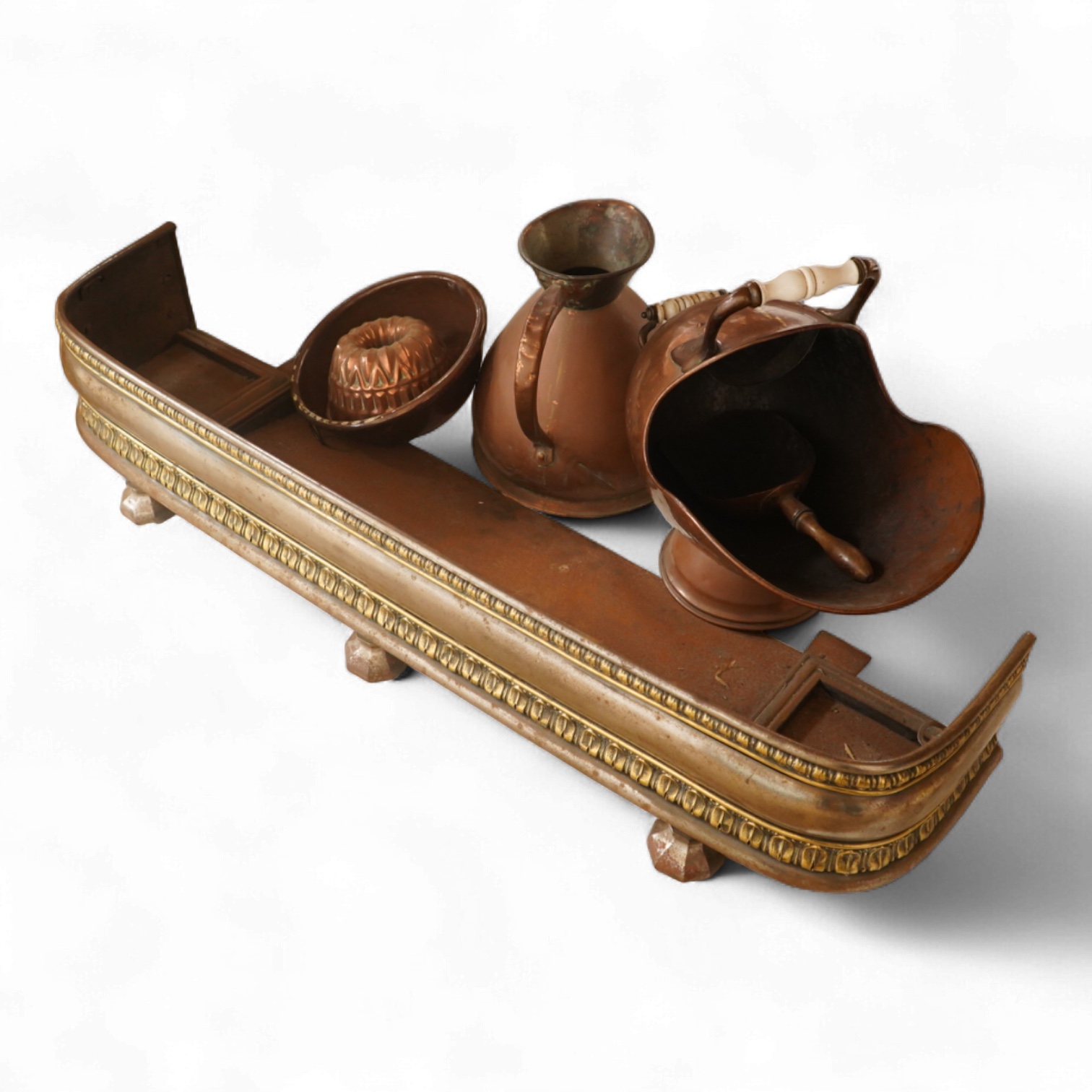 A collection of metalware to include a steel and brass fender, a helmet scuttle, 19th century jelly mould and a harvest jug
